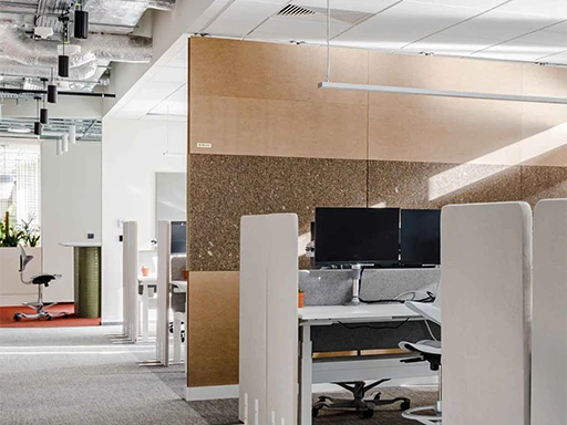 Modern open-plan office with ergonomic chairs, partitioned desks, and exposed industrial ceilings in a clean, professional workspace.